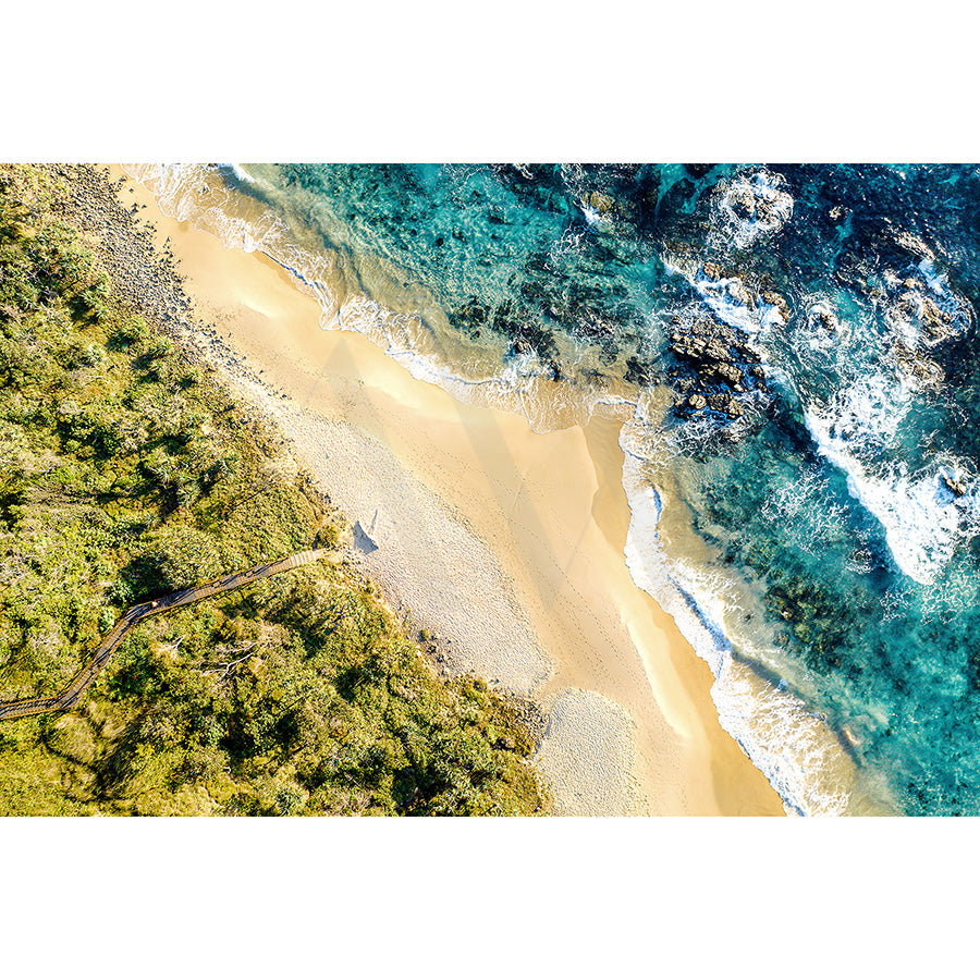 Experience the stunning Aerial view of Coolum Beach, captured in Drone Image 0058 from AWP Image Library, showcasing golden sands, clear turquoise waters with rocky formations, lush green borders, and a winding path leading to the shore.