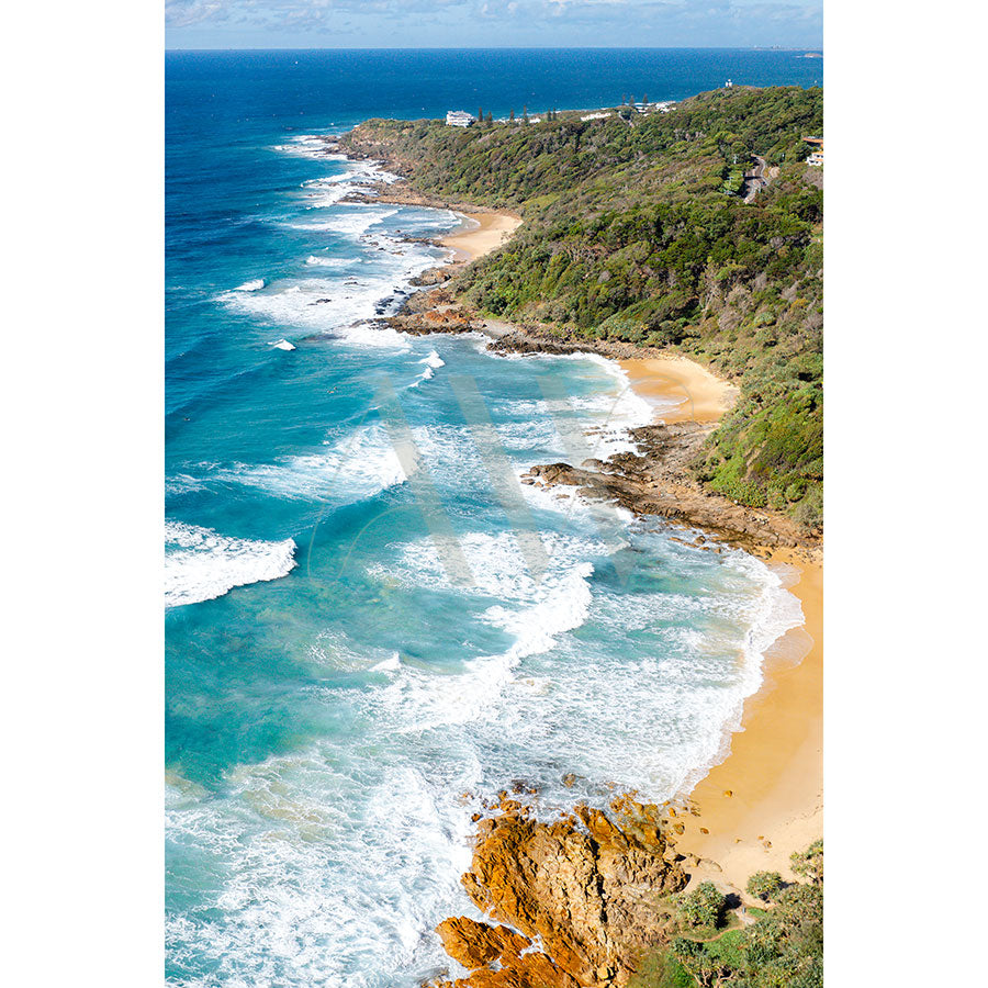 Product Name: Coolum Beach Drone Image 0321 by AWP Image Library captures a scenic coastline with turquoise waves hitting a sandy beach, rocky outcrops, and lush greenery. The ocean meets the clear blue sky in the backdrop.