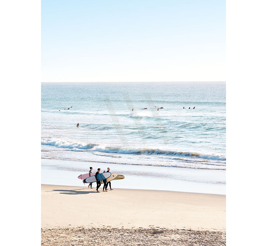 The Coolum Beach Image 9502 by AWP Image Library captures three surfers with their boards on a sandy beach, walking towards the ocean as others ride waves under a clear blue sky.