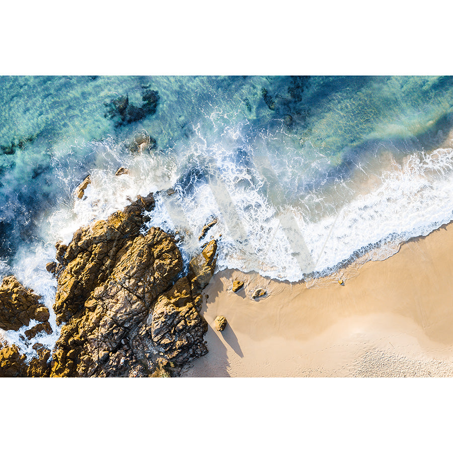 The Coolum Beach Drone Image 0956 from AWP Image Library captures turquoise waves crashing onto beige sand, rocky formations creating frothy surf patterns, and shadows highlighting the textures of rocks and water.