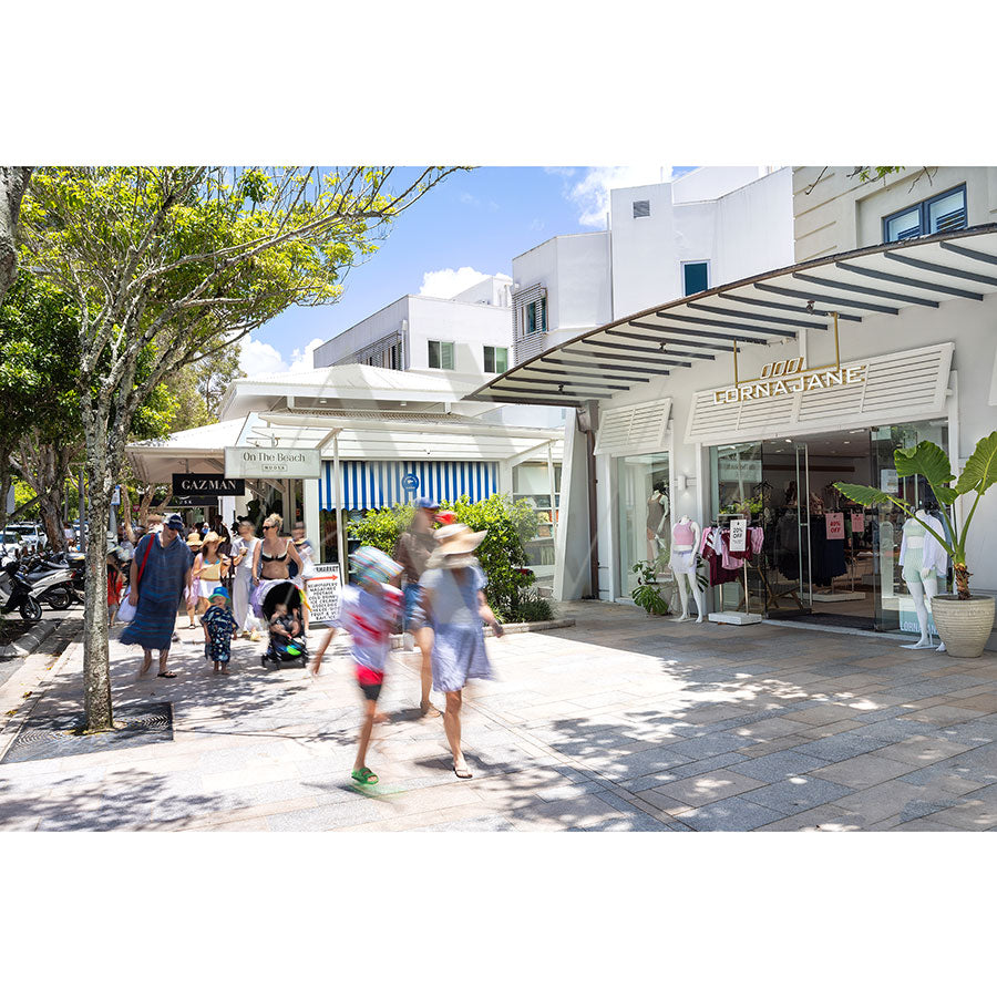 Hastings Street Image 5531 by AWP Image Library shows a bustling shopping street with people passing boutique shops like the FORMAFANT clothing store, tree-lined sidewalks, and a clear, sunny Noosa sky.