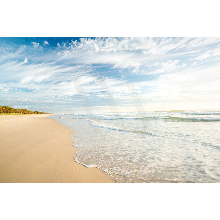 The Kingscliffe Beach Image 0628 from AWP Image Library captures a serene scene with gentle waves on golden sand, wispy clouds in the sky, and footprints stretching under a bright, clear blue horizon.
