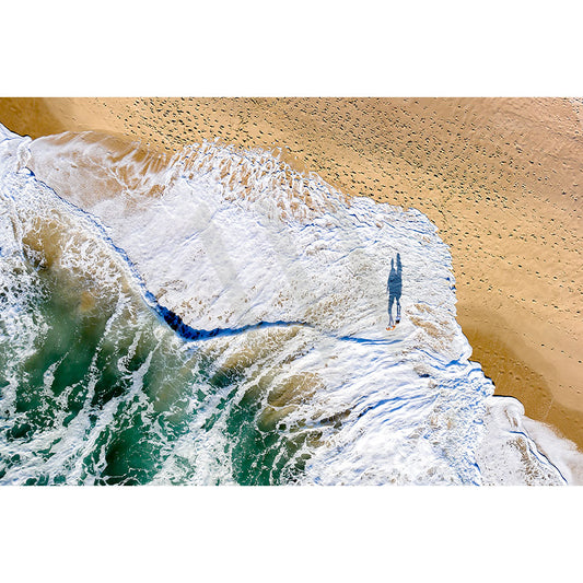AWP Image Librarys Mudjimba Beach Drone Image 0193 captures an early morning scene of a lone walker on the beach, leaving footprints in the sand. Foamy waves contrast with the blue ocean and golden sand.
